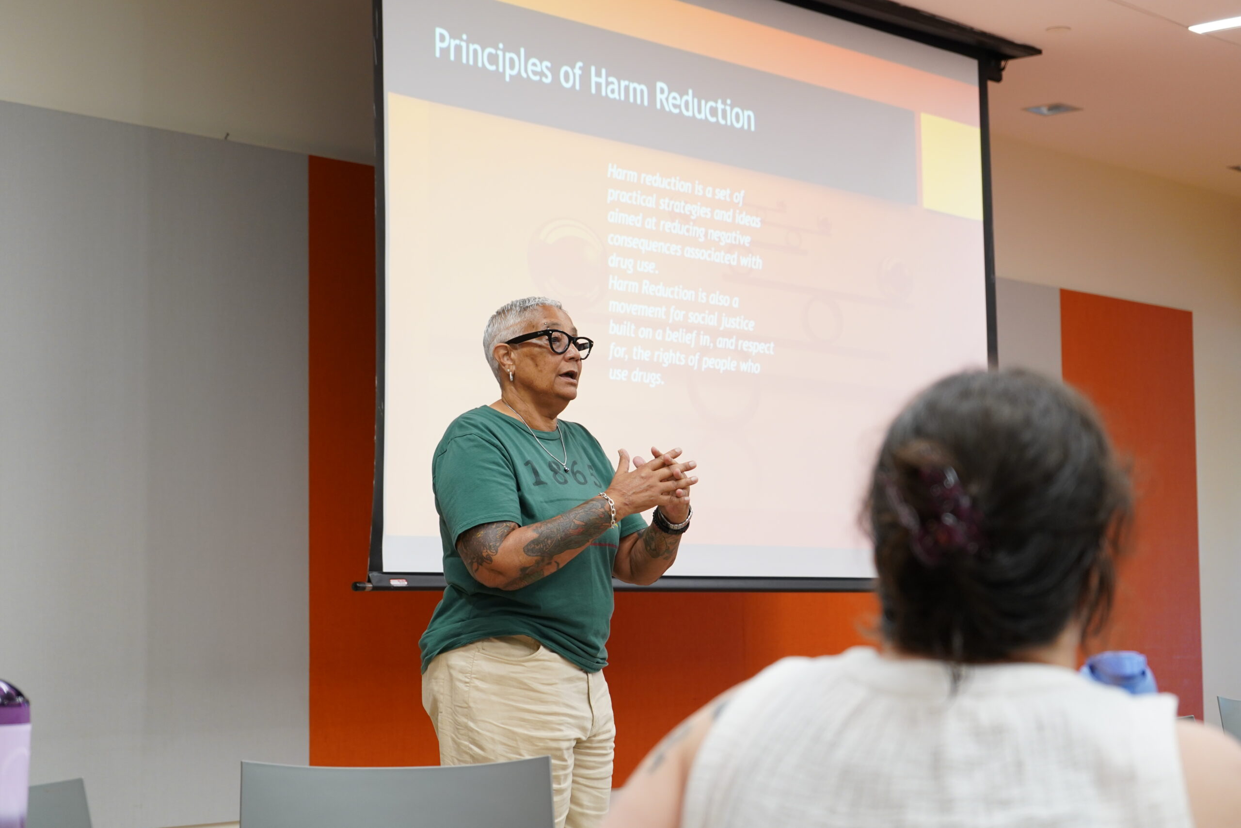 Facilitator presenting a slide titled Principles of Harm Reduction at a MAHRWC training