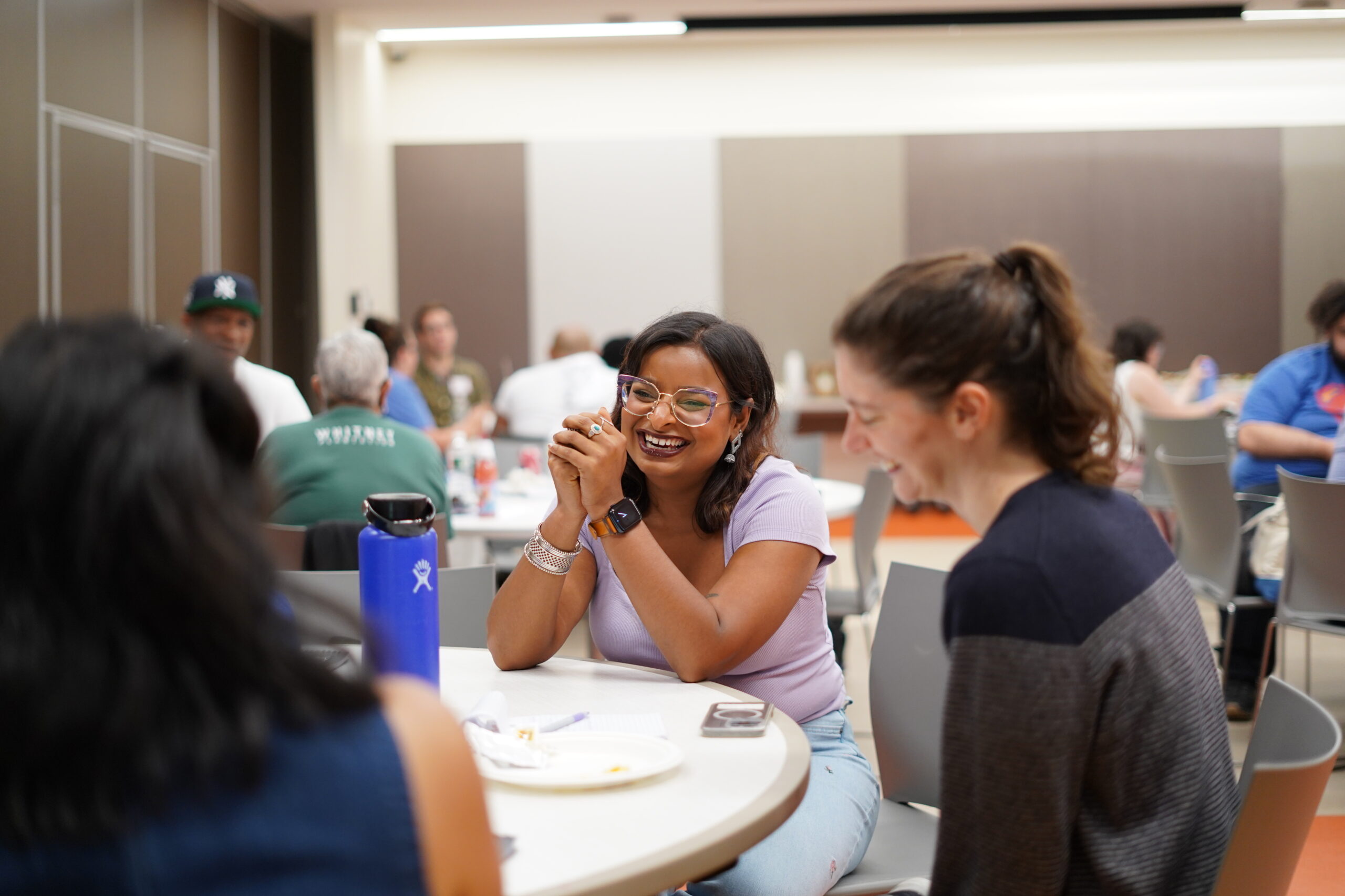 Participant in glasses smiling with her hands clasped during a table discussion at a MAHRWC harm reduction training
