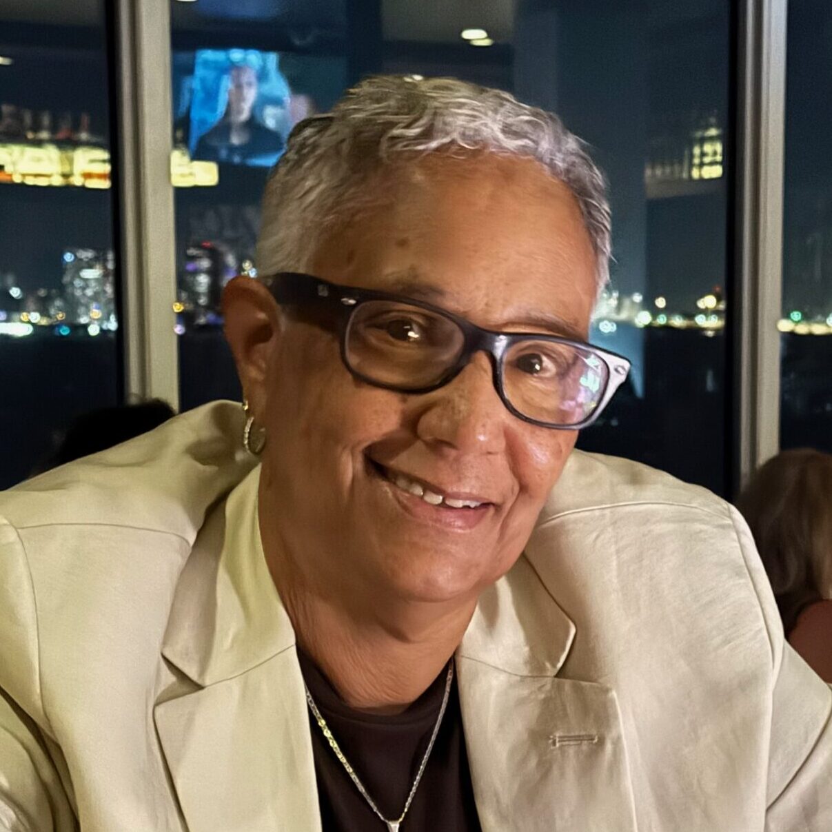 Headshot of Joy Rucker, smiling wearing a beige blazer